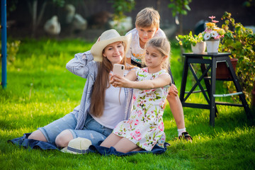 Fototapeta premium Young mother with pretty daughter and handsome son make photo in backyard