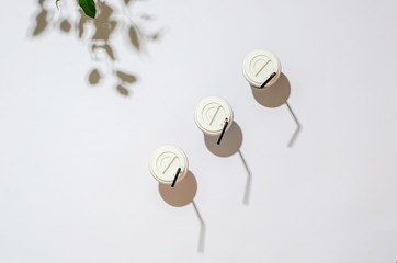 Bright paper coffee containers with a white lid and brown plastic tubes and shadows on a white background
