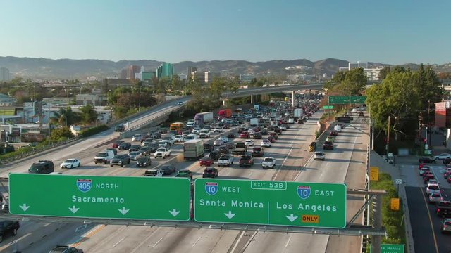 Aerial view of road signs, freeway and interstate traffic at I-405 and I-10 intersection in urban West Los Angeles with cars on a sunny day.