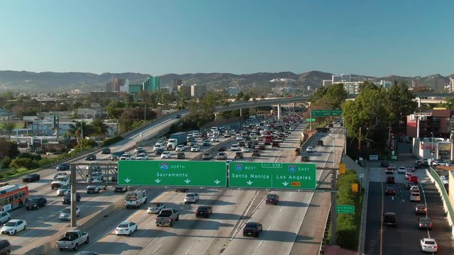 Drone shot of street signs, road and interstate traffic jam at I-405 and I-10 intersection in urban Los Angeles with cars on a sunny day.