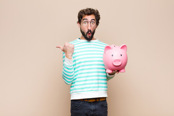 young cool man holding a piggy bank against clean wall