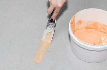 Female hand with a putty knifeapplies paste to a hole in the concrete. Close up