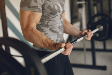 Sports man in the gym. A man performs exercises. Guy in a gray t-shirt