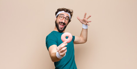 young sports man having a snack holding a pink sugar donut
