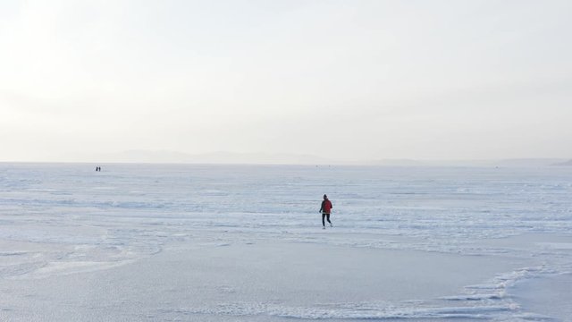 Aerial view of a sportsman running on white ice of beautiful frozen Amur bay in winter. Vladivostok, Russia