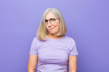 senior or middle age pretty woman feeling confused and doubtful, wondering or trying to choose or...