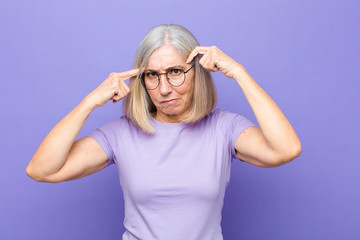 senior or middle age pretty woman with a serious and concentrated look, brainstorming and thinking about a challenging problem