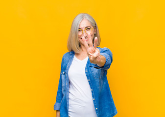 senior or middle age pretty woman smiling and looking friendly, showing number three or third with...