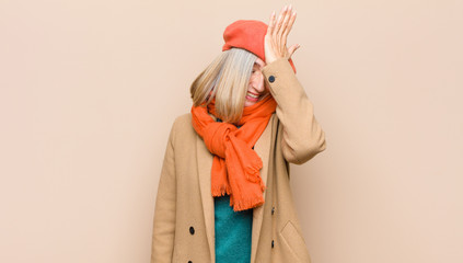 senior or middle age pretty woman raising palm to forehead thinking oops, after making a stupid...