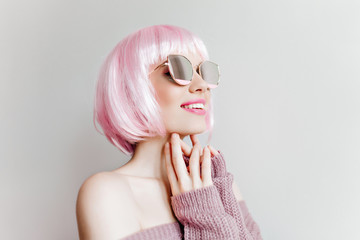 Close-up portrait of interested fashionable girl in stylish peruke. Indoor photo of enchanting lovely woman in sparkle sunglasses posing in studio.