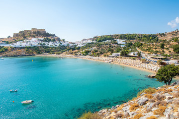 Fototapeta na wymiar Lindos beach and white houses of village of Lindos and Acropolis in background (Rhodes, Greece)