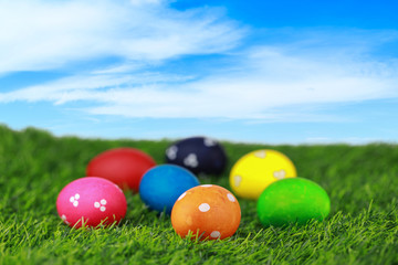 Group colorful and decorated beautiful easter eggs on green grass in nature with blue sky background. Advertising image Easter festival concept with free space.