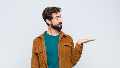 young handsome man feeling happy and smiling casually, looking to an object or concept held on the...