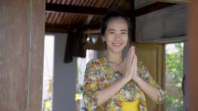 welcome greeting from asian javanese woman standing in front traditional house