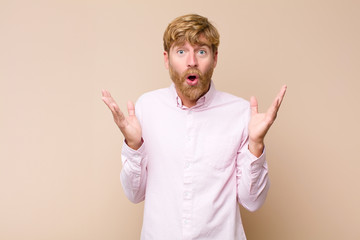 young blonde man feeling happy, excited, surprised or shocked, smiling and astonished at something...