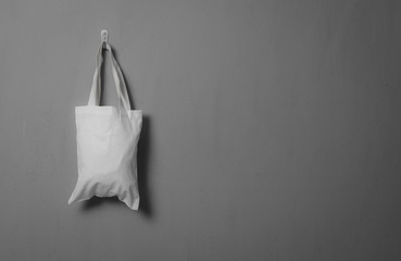White fabric bag hanging on grey concrete textured copy space background