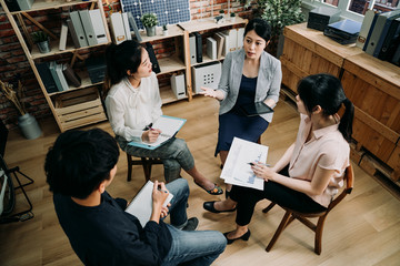 top view group of office staffs sitting in circle and having meeting together in board room. creative team work of engineers discussing about renewable energy project in eco friendly company.