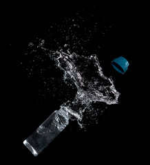 Bottle of drinking water splashing out isolated on black