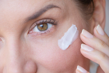  woman applies wrinkle cream on lower eyelid