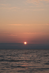 Fototapeta premium Red soft frosted sunset over the sea. Red disk of the sun