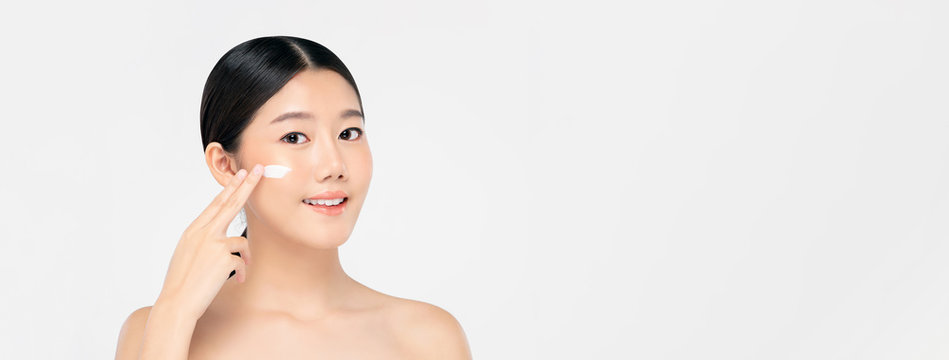 Young Beautiful Asian Woman Applying Cream To Face On Banner Background