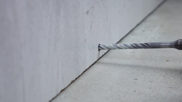 Close up on makes a hole in a concrete wall with hammer drill