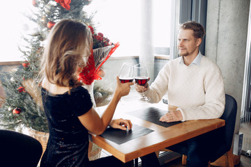 Couple in a restaurant. Lady in a black dress. Woman drinking a vine