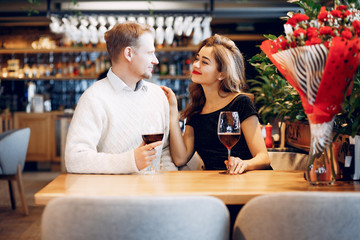 Couple in a restaurant. Lady in a black dress. Woman drinking a vine