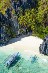 View from above, aerial view the Entalula Beach, a white sand beach surrounded by rocky formations and bathed by a crystal clear sea. Entalula island, Bacuit Bay, El Nido, Palawan, Philippines.