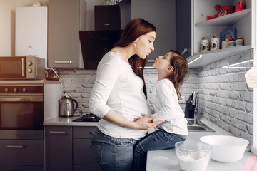 Pregnant mother with a daughter. Family in a kitchen