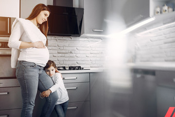 Pregnant mother with a daughter. Family in a kitchen