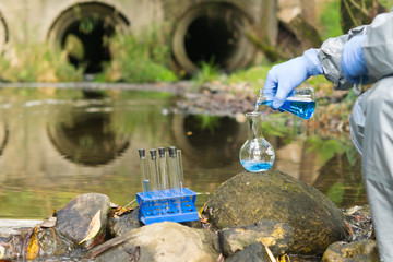 environmental biologist in a protective suit on the shore of a reservoir conducts an express test...