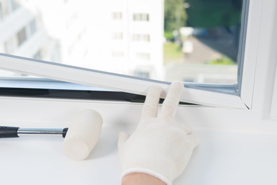 Window Installation Worker Inserts Glass Into The Frame And Fastens It With A Rubber Mallet, Rear View, Close-up