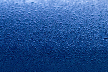 Rain drop on dark blue surface. Spring morning mood. Bright background or wallpaper. Texture of water droplets.