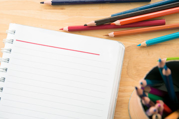 top view notebook paper. Colorful colored Pencils on wooden table.