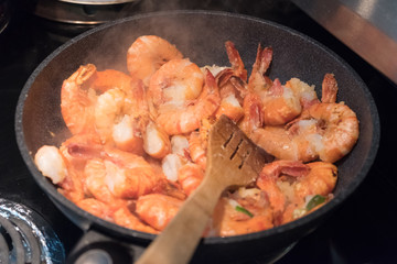 Homemade shrimp dish in non-stick pan with wooden spatula