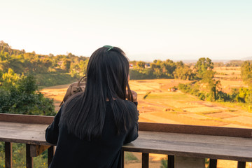 Warm Tone. Young Woman looking view of the mountains from wooden balcony at View point