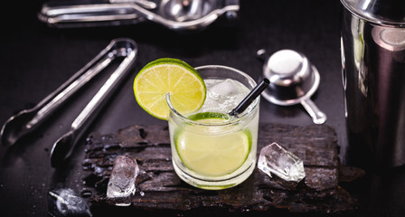 Brazilian caipirinha, typical Brazilian cocktail made with lemon and sugar with cachaça or vodka. Drink with black background and space for text.