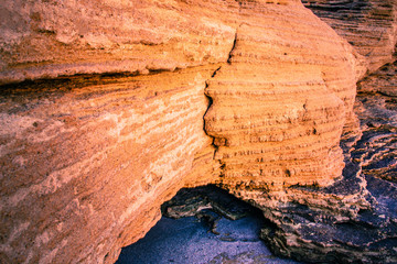 Sandy beach rocks colored in orange under the rays of the rising sun.