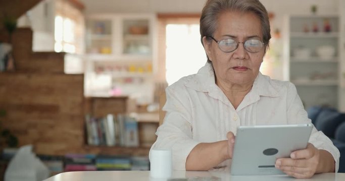 Closeup face of senior women trying to use tablet with concentration. Senior woman using tablet at home alone. Technology concept. 4k resolution.