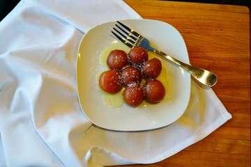 A dessert dish of sweet gulab jamun sugar balls at an Indian restaurant