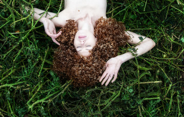 portrait of sexy young woman lying in tomato plants after harvest, with many hortensia flowers around the head instead of her hair, copy space.