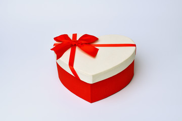 Box. Heart-shaped gift box with red ribbon stands in the middle on a blue-gray background. Valentine's day and Birthday