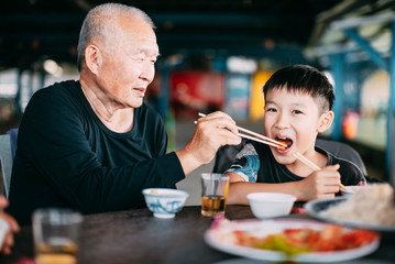 Fototapeta na wymiar Granfather feeding her grandson in restaurant