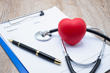 Red heart medical stethoscope and black pen Put on the doctor's charging plate.Health examination concept Health insurance. Medical health. Taking care of yourself as ordered by a doctor.Close up.