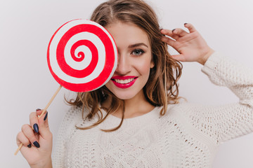 Close-up shot of female model with red lipstick holding lollipop on white background