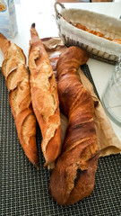 French baguettes on a table next to a bakery basket. 