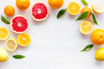 Citrus fruits frame - halfs of lemons, grapefruits, leaves - on white background top-down copy space
