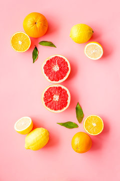 Citrus pattern. Cut lemon and grapefruits and leaves on pink background top-down