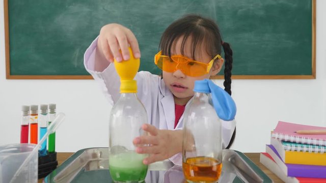 Little asian girl doing science experiment in classroom.